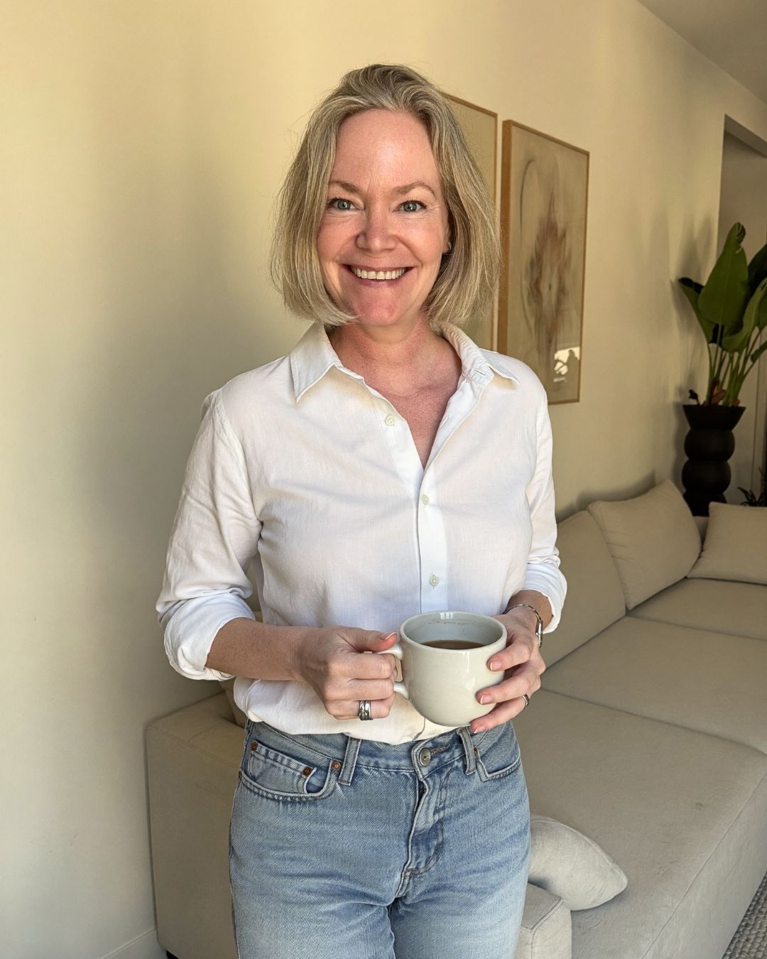 Nina Kolari holding a mug in her living room