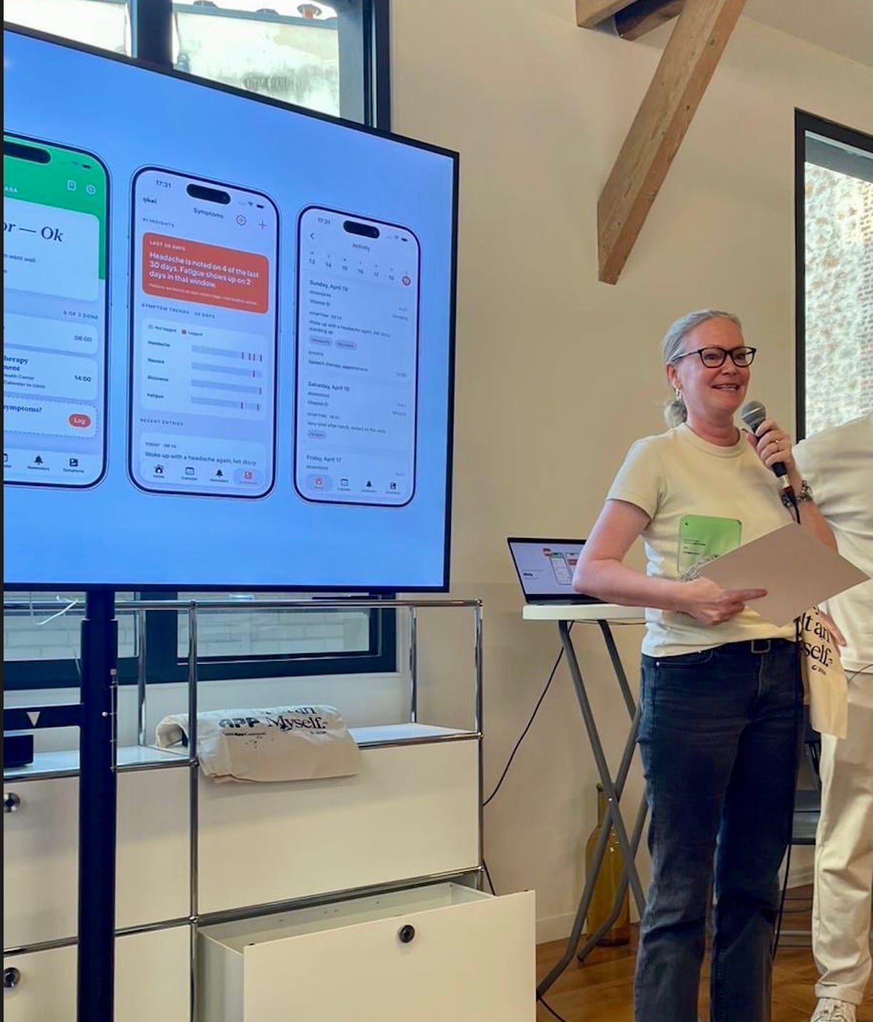 Nina Kolari presenting a mobile app on stage at a hackathon